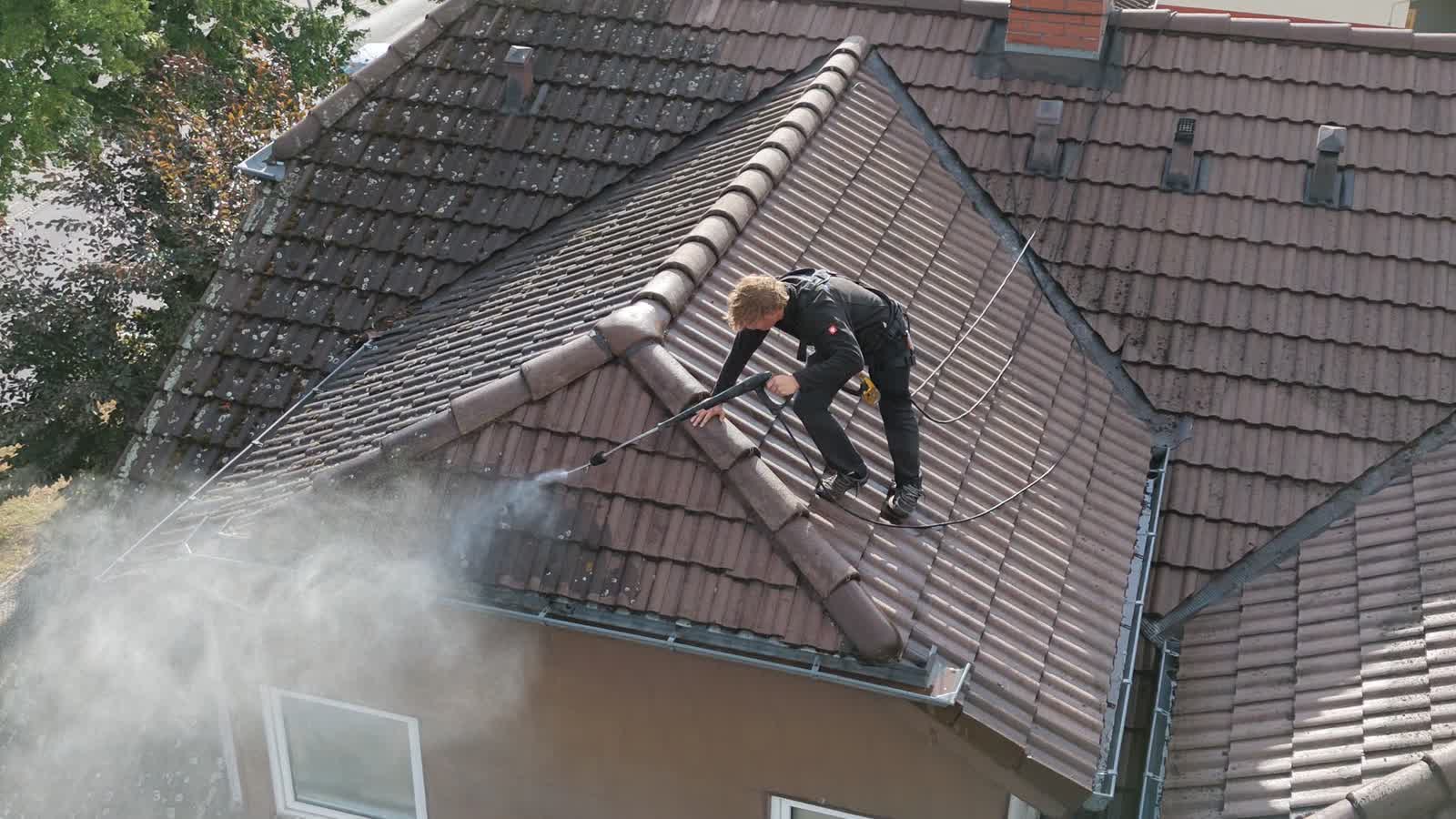 Reinigung mit der Niederdrucklanze auf dem First, Arbeitskleidung und Sicherungsgurt